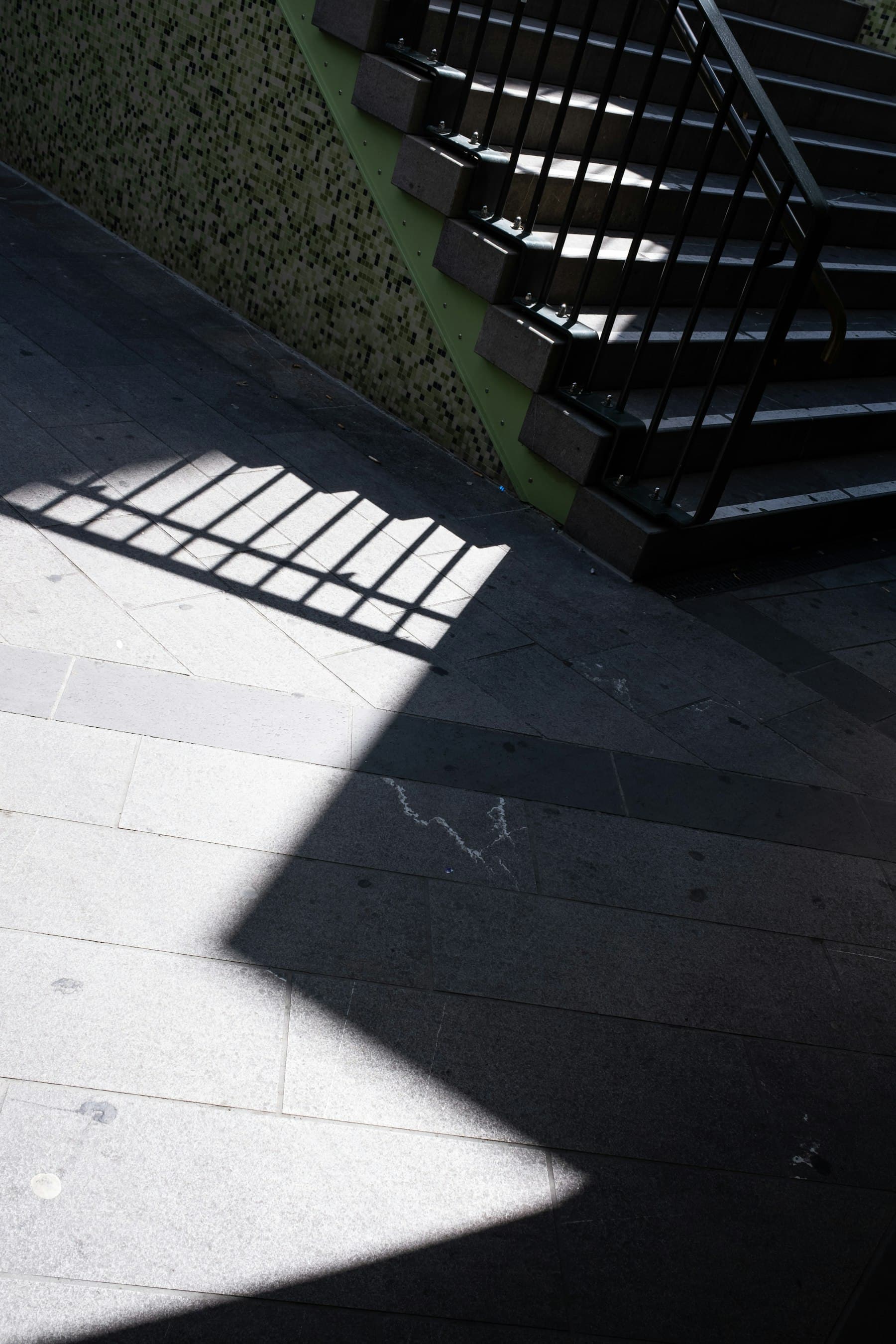 Escalera con la sombra recortada de una barandilla sobre el suelo